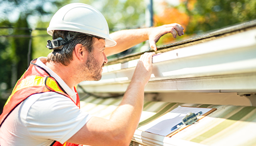a man inspecting roof shingles