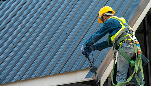 a worker drilling on a roof